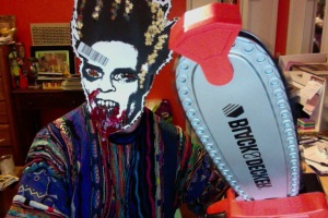 Thomas Outt in paper mask made from Midnites For Maniacs Poster designed by Jesse Hawthorne Ficks, brandishing a fake chainsaw, all forlorn about not being cast in the remake of THE TEXAS CHAINSAW MASSACRE!  